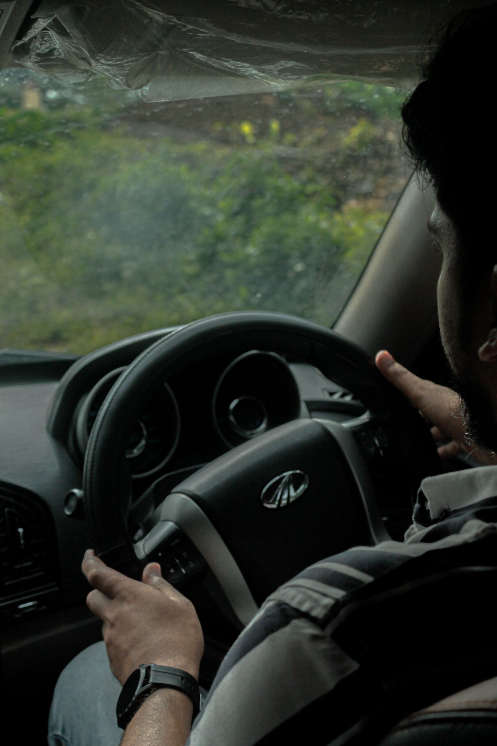 Home Close-up of a man driving a car, focusing on the steering wheel and interior setup.